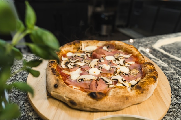 Vue rapprochée de la pizza avec des champignons et du bacon sur une planche en bois cuisine italienne