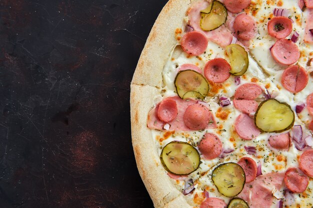 Vue rapprochée de pizza avec frankfurter, jambon, concombre mariné et oignon