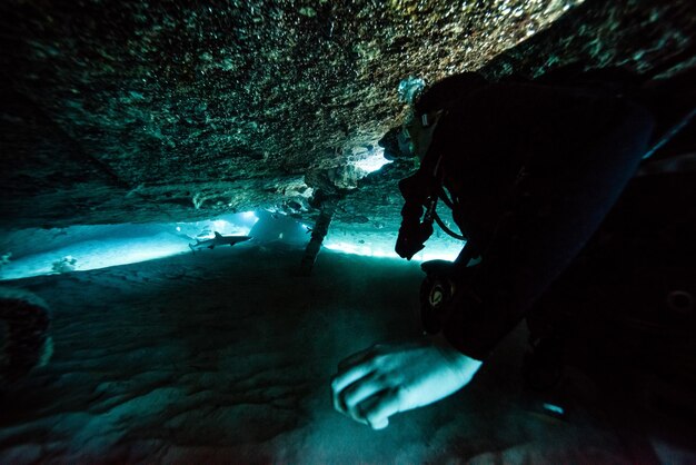 Photo vue rapprochée d'un plongeur nageant près d'une formation rocheuse sous-marine