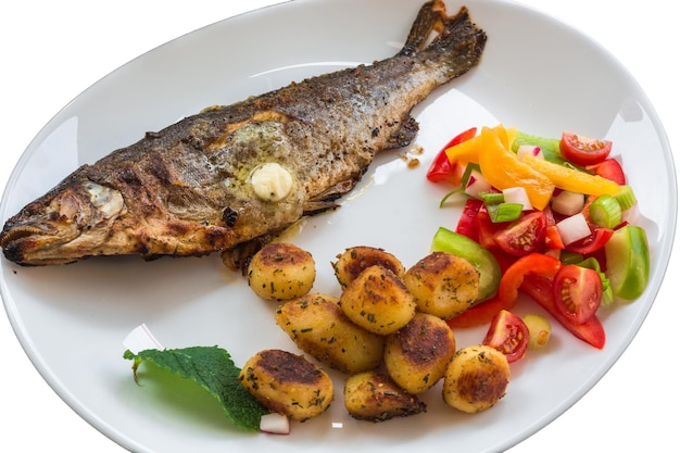 Vue rapprochée d'un poisson rôti avec des légumes dans une assiette