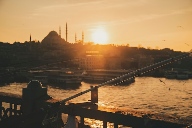Photo vue rapprochée des poteaux de pêcheur depuis la silhouette d'istanbul pendant le coucher du soleil