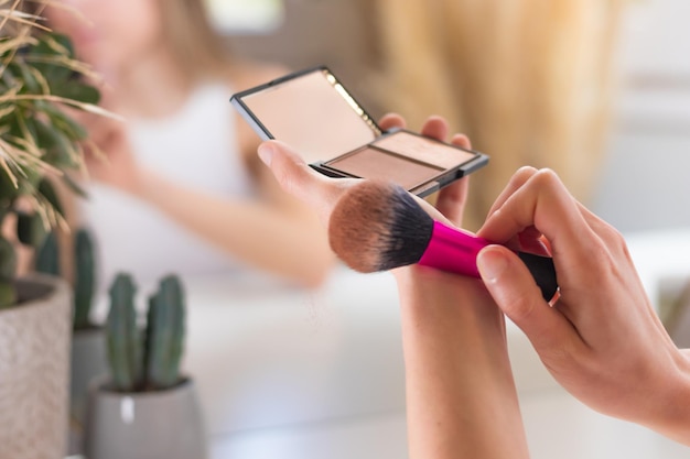 Vue rapprochée de la poudre bronzante et de la brosse de maquillage secouant l'excès de poudre libre