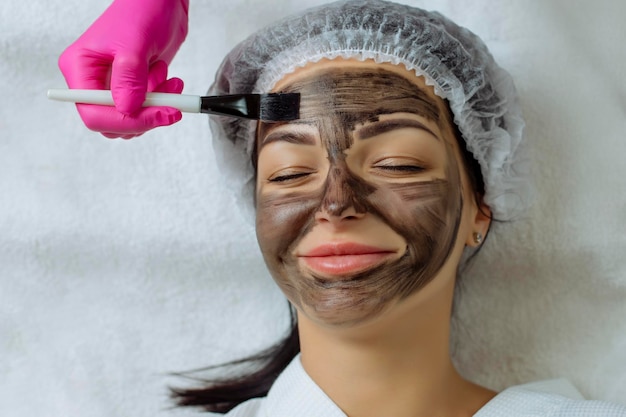 Photo vue rapprochée de la procédure de peeling au carbone pour le visage d'une femme d'âge moyen.