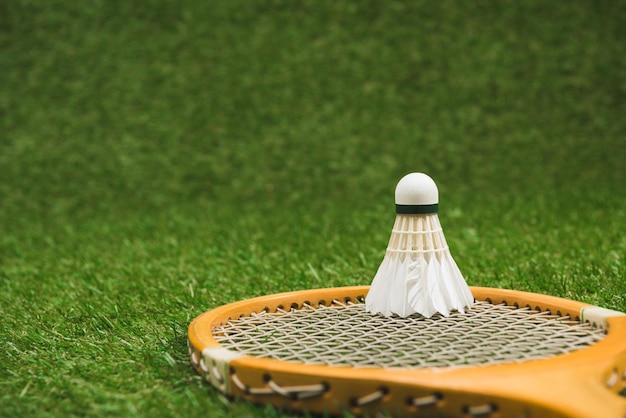 Vue rapprochée de la raquette de badminton et du volant sur la pelouse verte