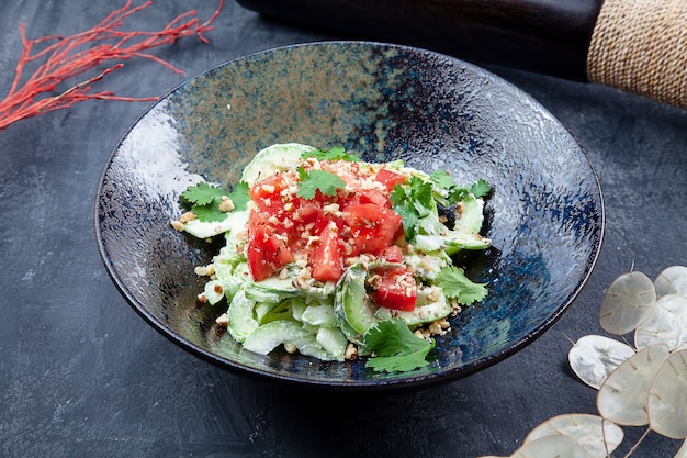 Vue rapprochée sur un saladier frais. Salade de tomate, épinards et roquette dans un bol sombre sur fond sombre. Nourriture végétalienne saine pour le déjeuner. Fond de photo de nourriture.