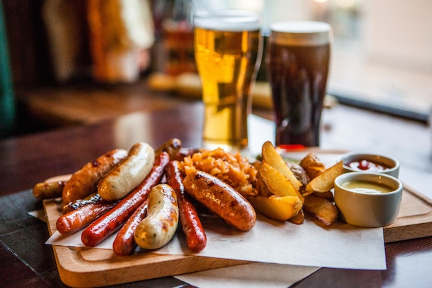 Vue rapprochée des saucisses et des frites servies avec des bières sur la table