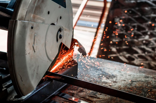 Photo vue rapprochée d'une scie électrique coupant du métal en usine