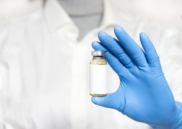 Vue rapprochée sélective d'une main portant un gant tout en tenant un vaccin