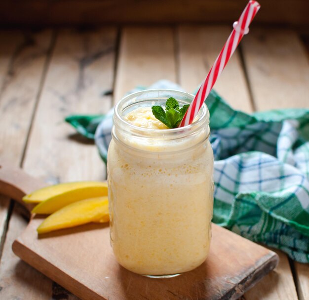 Photo vue rapprochée d'un smoothie à la mangue dans un pot sur une table en bois