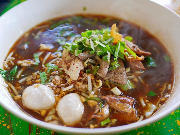 Photo vue rapprochée d'une soupe de nouilles thaïlandaises fraîches avec du porc et son délicieux bouillon épais guay tiao nam tok moo