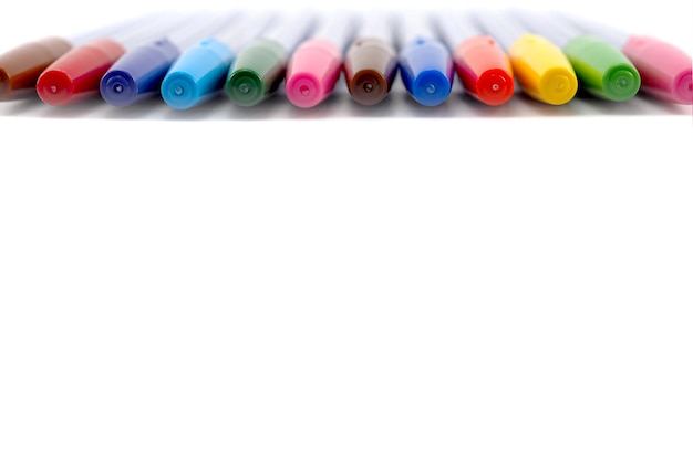 Vue rapprochée de stylos colorés disposés sur fond blanc