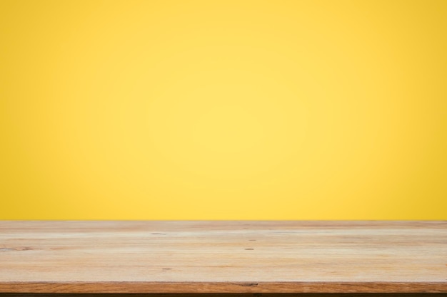 Photo vue rapprochée d'une table en bois contre un mur jaune