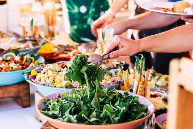 Vue rapprochée d'une table pleine de nourriture avec quelqu'un qui prend des légumes de la table pour célébrer