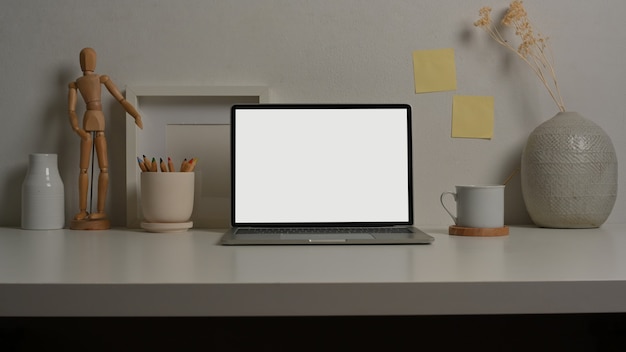 Vue rapprochée de la table de travail avec des fournitures et des décorations pour ordinateur portable dans la salle de bureau à domicile