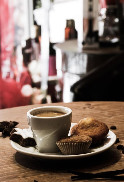 Photo vue rapprochée d'une tasse de café avec des cupcakes sur la table