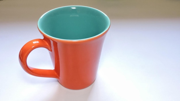 Vue rapprochée d'une tasse de café orange sur fond blanc
