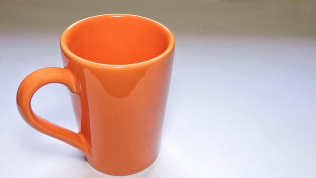 Vue rapprochée d'une tasse de café orange sur fond blanc