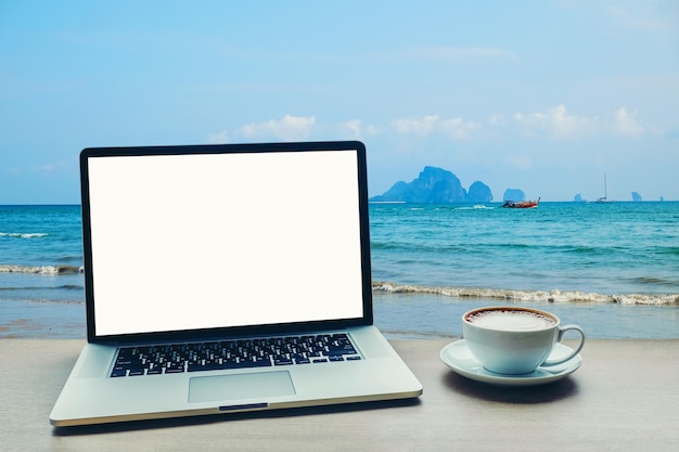 Vue rapprochée d'une tasse de café par la mer contre le ciel