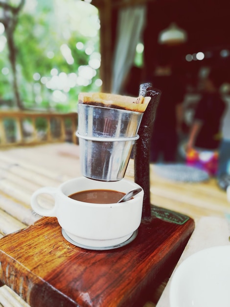 Photo vue rapprochée de la tasse de café sous le filtre à café sur la table