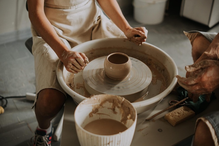 Photo vue rapprochée d'une tasse en céramique tournant sur la roue du potier et des mains moulant de l'argile