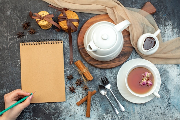 Vue rapprochée d'une tasse de thé noir et d'une bouilloire sur des biscuits pour ordinateur portable en bois sur fond de glace