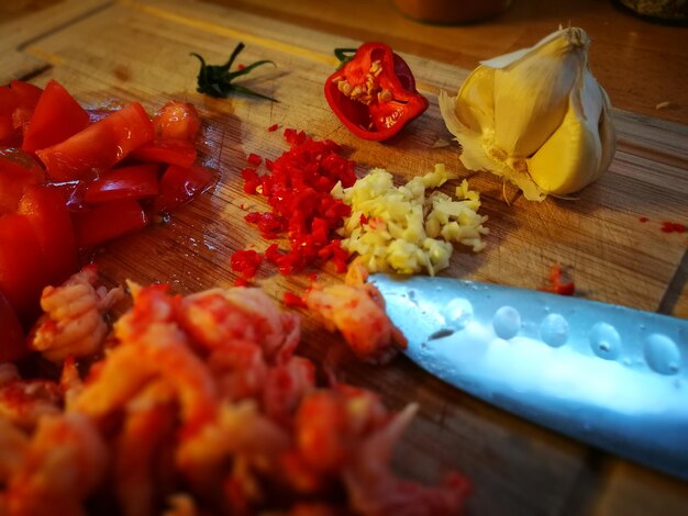 Photo vue rapprochée de la tomate et de l'ail hachés au couteau sur la planche à couper