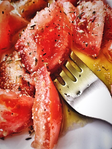 Photo vue rapprochée de tomates tranchées avec une fourchette dans l'assiette