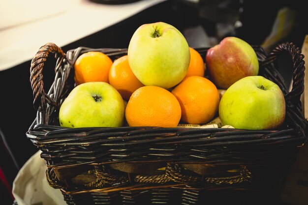 Vue rapprochée tonique du panier plein d'oranges et de pommes vertes