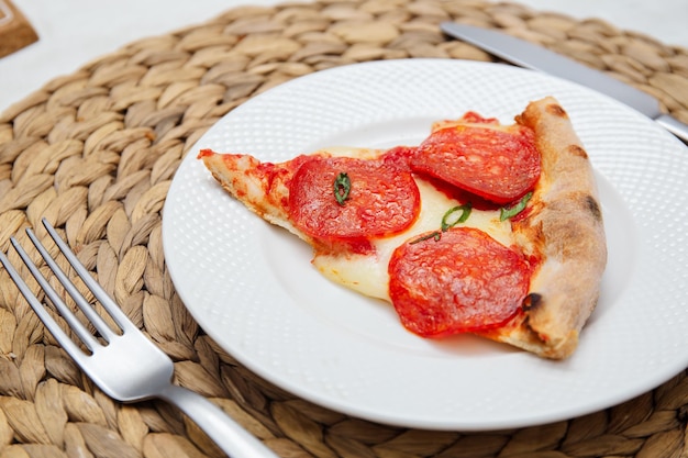 Photo vue rapprochée d'une tranche de pizza au pepperoni sur l'assiette