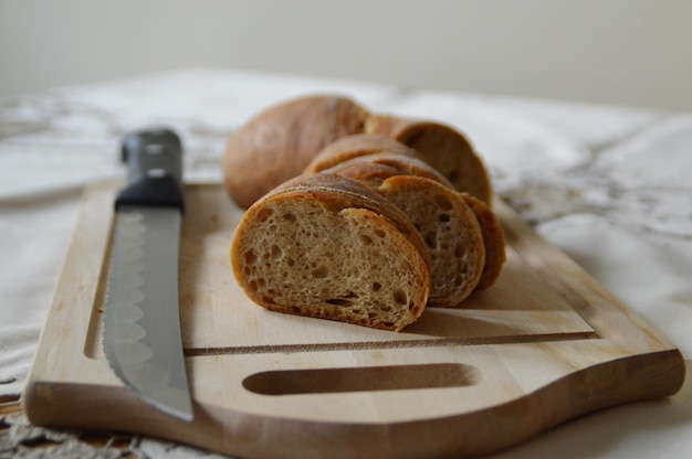 Vue rapprochée de tranches de pain au couteau sur la planche à couper à table