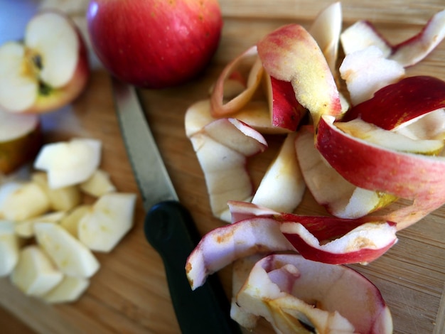Vue rapprochée de tranches de pommes sur la planche à couper avec un couteau dans la cuisine à la maison