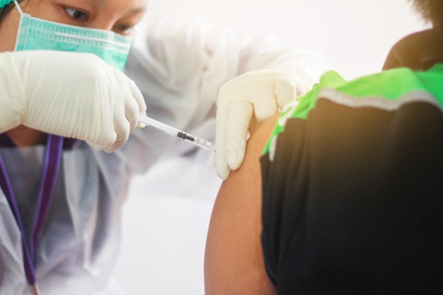 Vue rapprochée d'un vaccin se faisant vacciner dans son bras pendant la pandémie du virus corona. patient dans un masque médical. Vaccin contre le Covid-19 ou le coronavirus