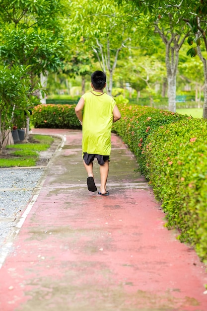 Vue rare du jeune garçon asiatique courir dans le jardin