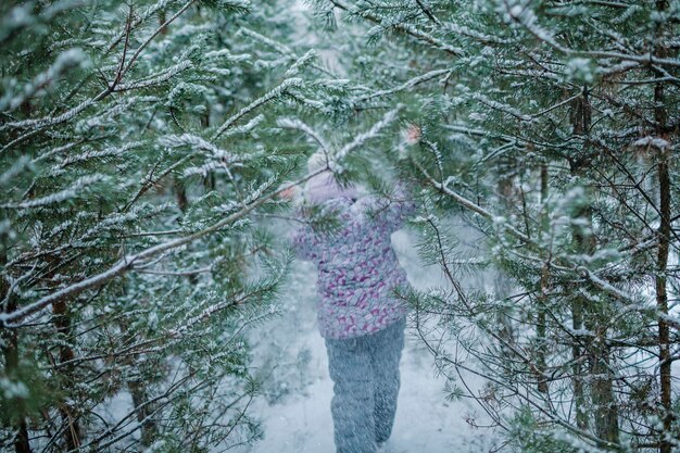 Vue rare de fille pendant la marche en famille dans la forêt enneigée au pays des merveilles d'hiver par temps de retour