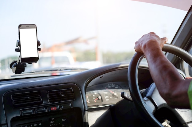 Vue recadrée Le conducteur utilise le téléphone pendant la conduite Téléphone intelligent moderne avec des bords arrondis Écran isolé pour la maquette Affichage de la navigation de la voiture en arrière-plan