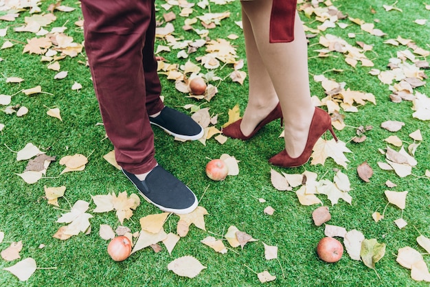 Vue recadrée du couple homme et femme pieds amoureux romantique en plein air avec des feuilles d'automne sur fond. Concept de mode de vie et de relations