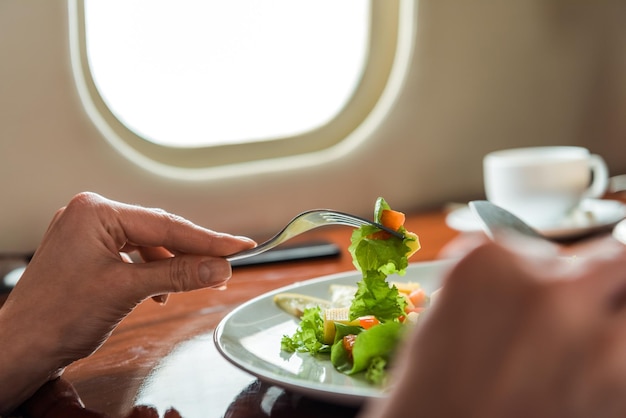 Photo vue recadrée d'une femme tenant des couverts près d'une salade savoureuse en jet privé