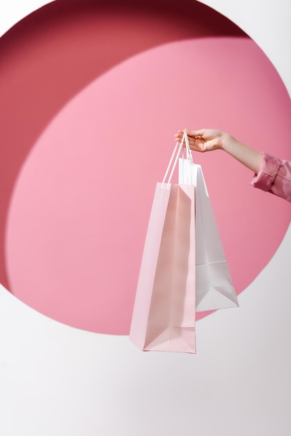 Photo vue recadrée d'une femme tenant des sacs à provisions sur rose et blanc