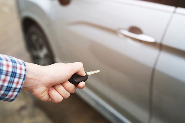 Vue recadrée de gros plan d'une main de l'homme en insérant la clé dans la serrure de porte d'une voiture