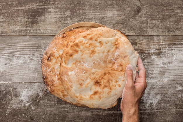 Vue recadrée de l'homme tenant du pain lavash sur une table en bois