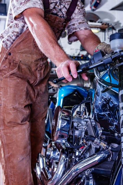 Photo vue recadrée d'un homme travaillant dans un garage réparant une moto et personnalisant