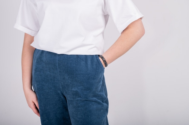 Vue recadrée de jeune femme en T-shirt surdimensionné blanc et pantalon bleu foncé isolé