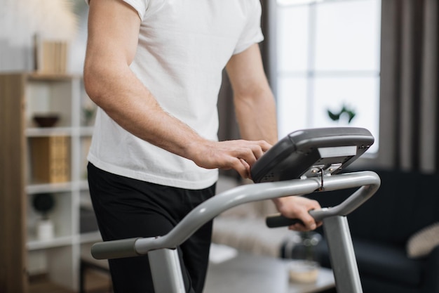 Vue recadrée des mains masculines tapant sur l'écran du panneau de commande du tapis roulant