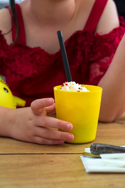 Vue recadrée d'une petite fille mignonne buvant un cocktail laiteux à partir d'un espace de copie de paille Concept d'été