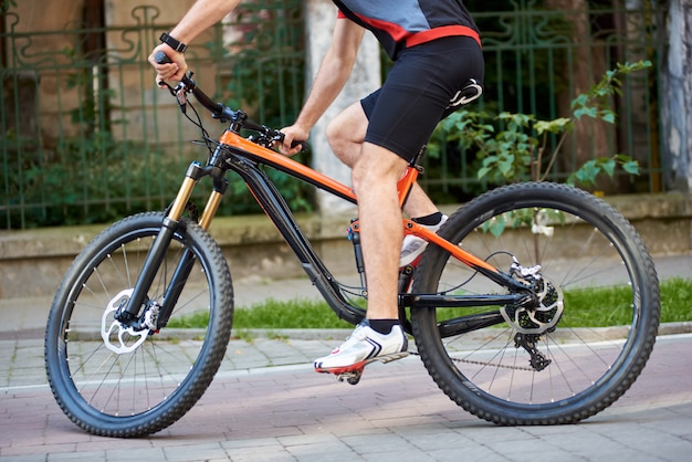 Vue de la récolte du cycliste masculin à vélo le long des rues pavées