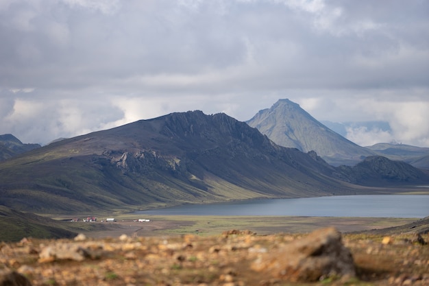 Vue sur le refuge de Hvanngil et le camping avec collines verdoyantes, ruisseau et lac. Sentier de randonnée Laugavegur, Islande.