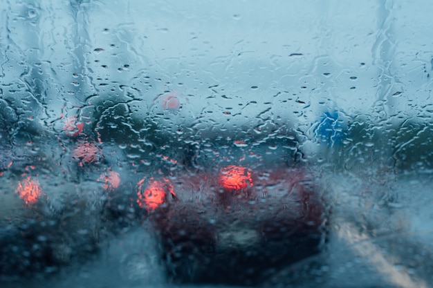 Vue sur la route à travers le pare-brise de la voiture avec des gouttes de pluie.