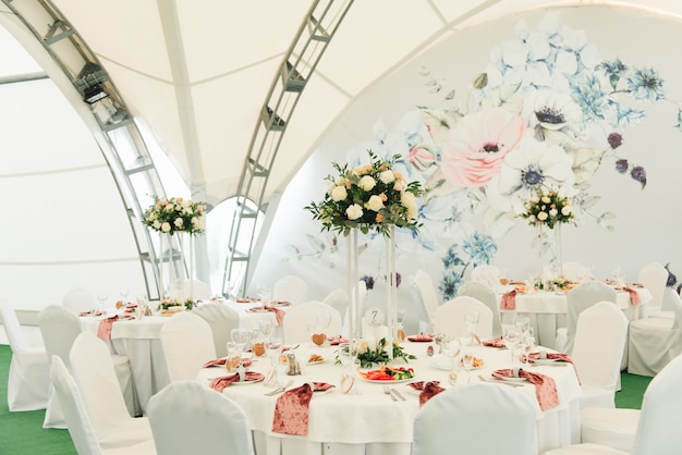 Vue sur la salle de mariage, la tente, les tables de mariage décorées de fleurs fraîches