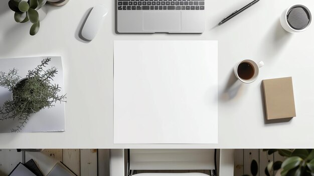 Vue supérieure d'un bureau avec un ordinateur portable, une tasse de café, un cahier, un stylo, une plante de souris et une feuille de papier blanche au centre