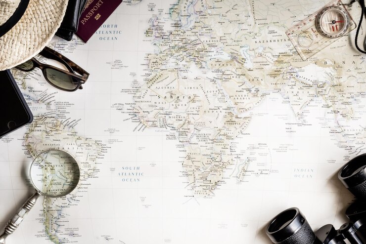 Photo vue supérieure d'une carte du monde avec un passeport, des jumelles, des lunettes de soleil, un concept de voyage